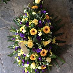 Vibrant gold and purple casket spray
